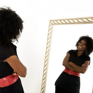 Ein positives Selbstbild - Frau lächelnd vor dem Spiegel