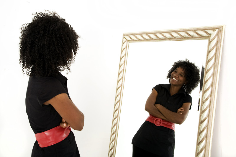 Ein positives Selbstbild - Frau lächelnd vor dem Spiegel