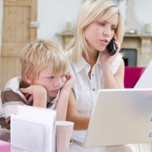 Abstand gewinnen - junge Frau die im Büro mit Laptop telefoniert, während der Junge sich langweilt